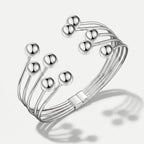 Damenarmband mit mehreren glatten Metallreihen und polierten Kugelenden, in Gold- oder Silberoptik am Handgelenk und in Detailansicht dargestellt